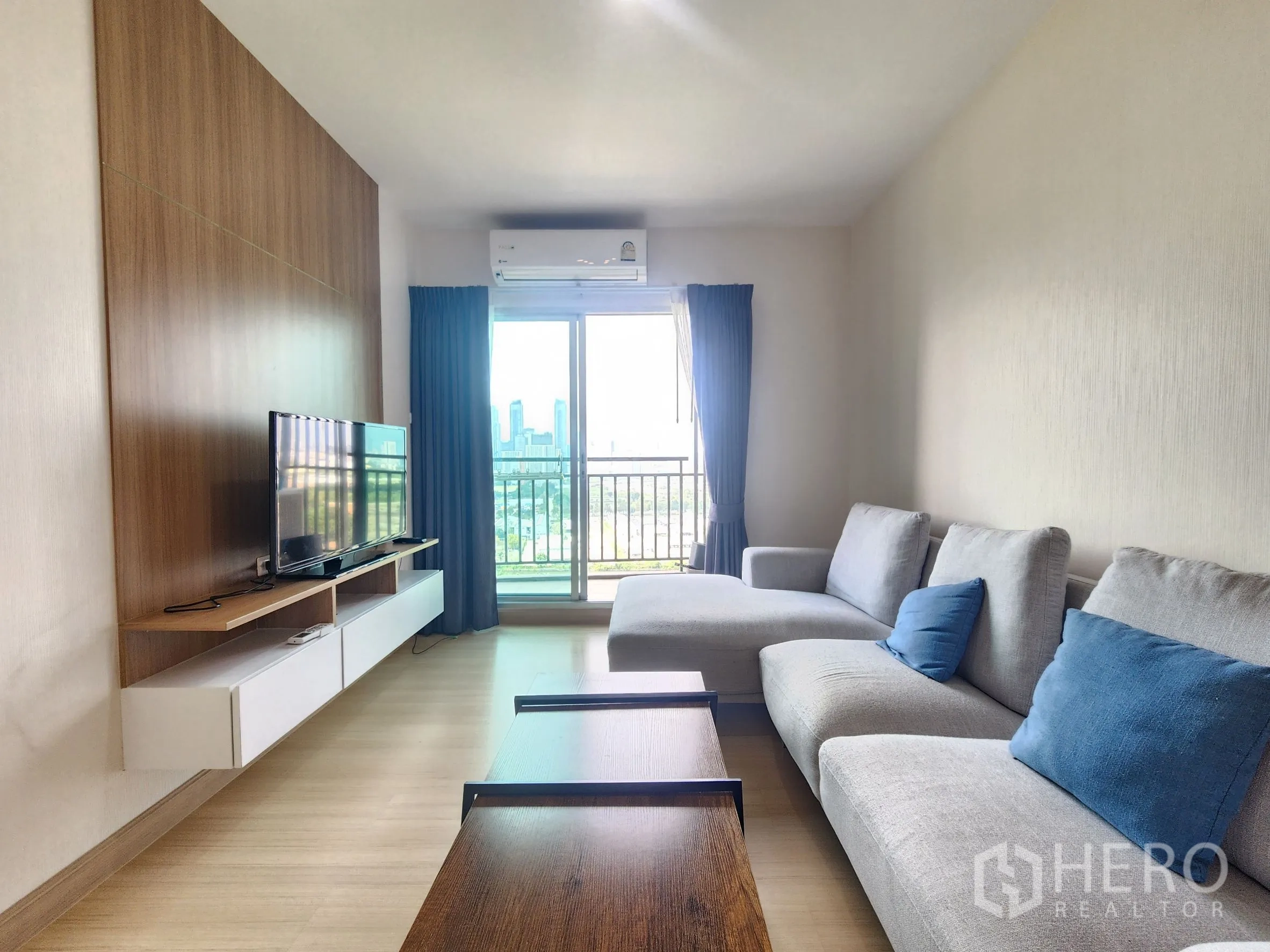 คอนโด for rent in Huai Khwang, Bangkok - ห้องนั่งเล่นมีทีวีบนชั้นลอย โซฟาขนาดใหญ่ และระเบียงถัดจากผนังไม้