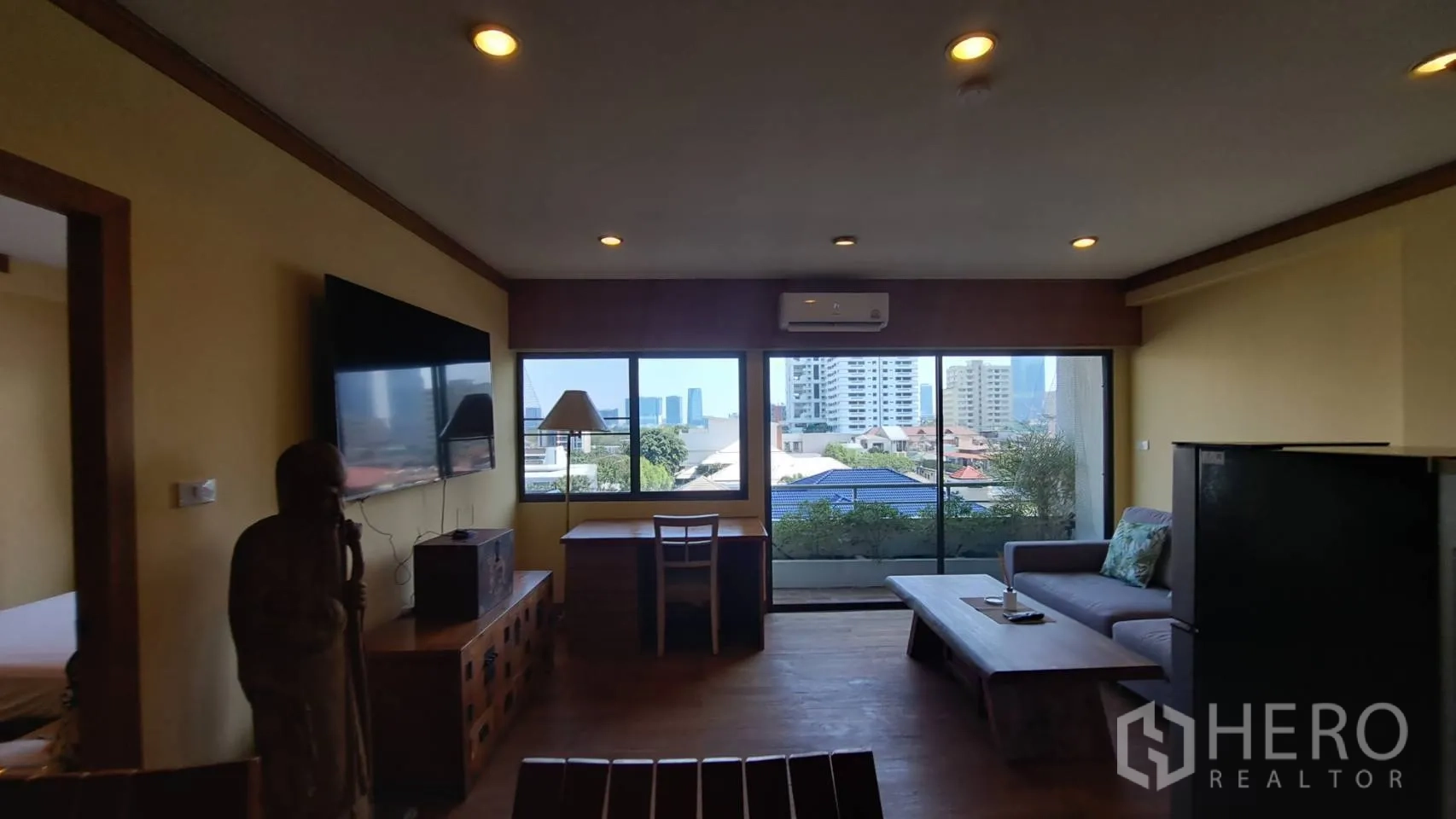 Condominium for rent in Khlong Toei, Bangkok - Living room facing wide windows and balcony, offering city views.