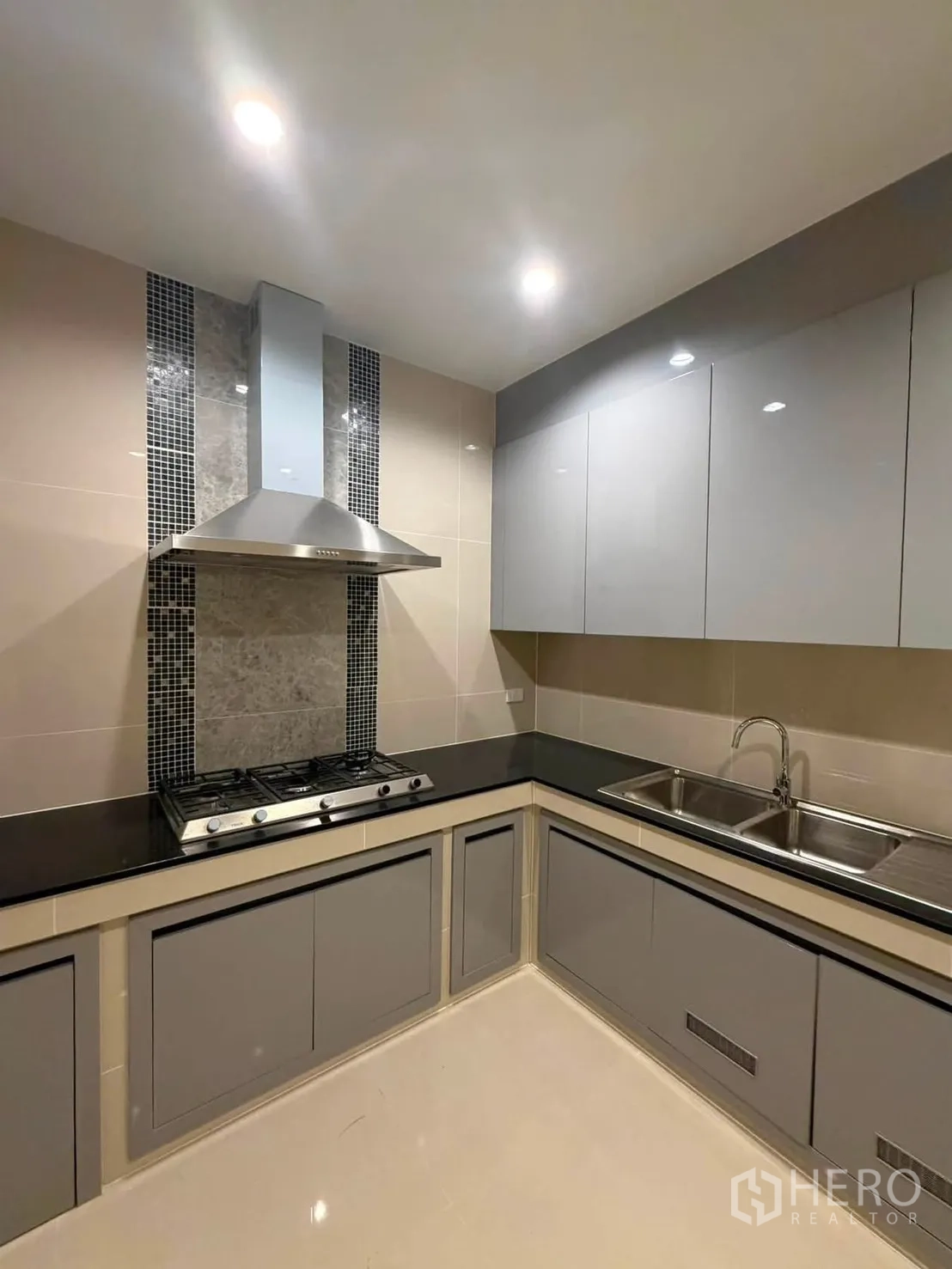 Detached House for rent or sale in Prawet, Bangkok - Closed L-shaped kitchen with gas hob, hood, and glossy cabinets.