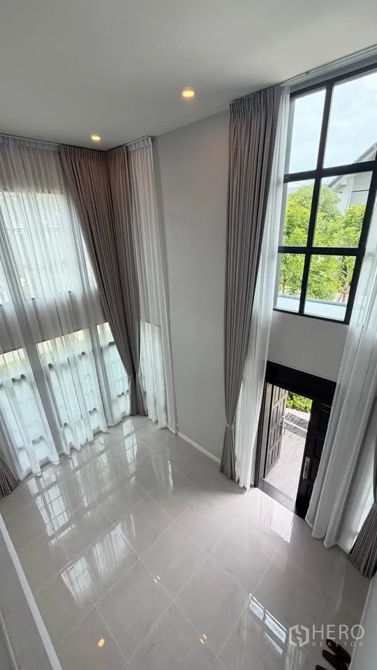 Detached House for rent in Bang Phli, Samut Prakan - Double-height living area with floor-to-ceiling windows and sheer curtains.