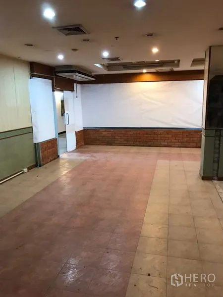 零售空间 出租在Bang Rak, Bangkok - 开放式店铺内景，射灯吊顶、后部出入口与砖饰墙，邻近BTS沙拉当站。