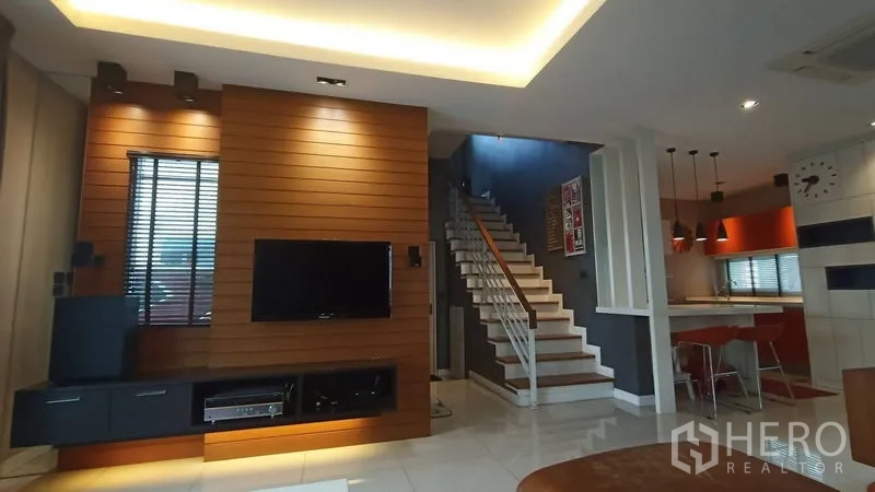 独立式住宅 出售在Prawet, Bangkok - 开放式起居区，木质电视背景墙、楼梯与吊灯厨房。