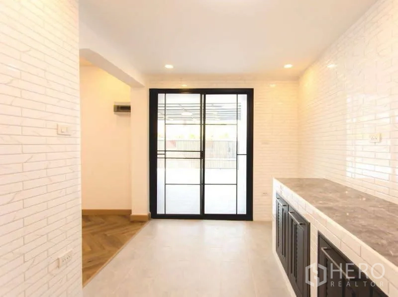 Detached House for sale in Wang Thonglang, Bangkok - Kitchen and dining space with stone countertop and sliding glass door opening to the terrace.