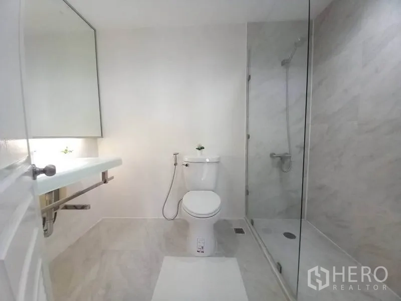 公寓 出租在Khlong Toei, Bangkok - 干净浴室，玻璃淋浴间、坐便器与悬空台盆。