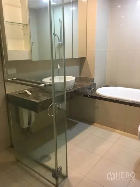 公寓 出租在Bang Rak, Bangkok - 浴室设玻璃淋浴间、台上盆石面台和浴缸。