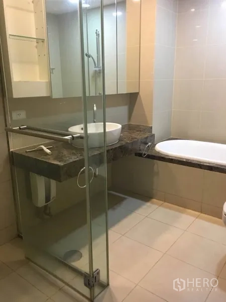 公寓 出租在Bang Rak, Bangkok - 浴室设玻璃淋浴间、台上盆石面台和浴缸。