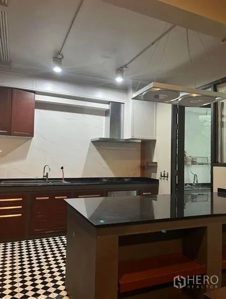 Townhouse for rent in Phaya Thai, Bangkok - Modern kitchen with granite countertops, island, stainless range hood, and checkerboard tile floor.