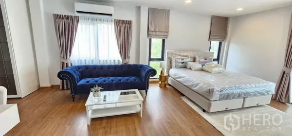 Detached House for rent - Bright bedroom featuring a blue velvet sofa, large windows and a neatly made bed on wood floors.