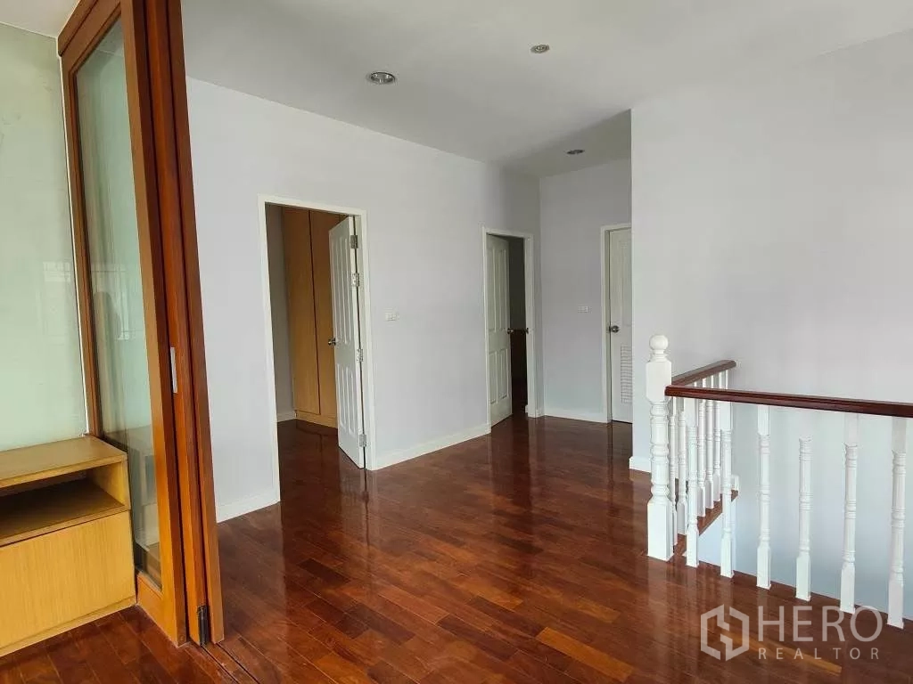 独立式住宅 出租或出售在Mueang Nonthaburi, Nonthaburi - 二层走廊，亮面木地板与白色栏杆。