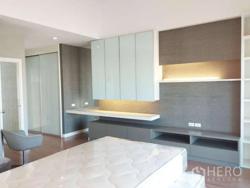 Townhouse for rent in Saphan Sung, Bangkok - Bedroom with backlit shelving, wall cabinets and warm wood floors.