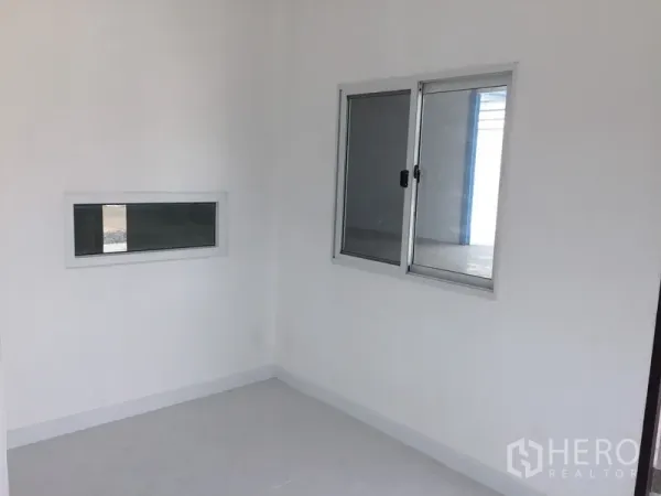 Factory for rent in Pathum Thani - Bright small office room with white walls, tile floor and aluminum sliding windows.