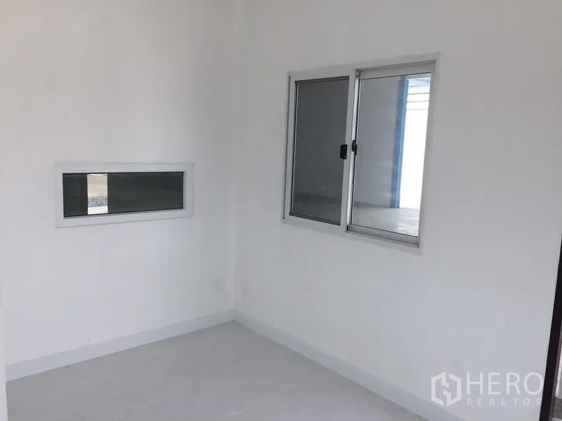 Factory for rent in Pathum Thani - Bright small office room with white walls, tile floor and aluminum sliding windows.