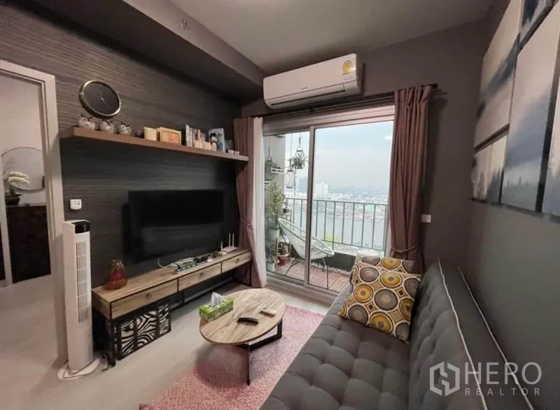 Condominium for sale in Bang Sue, Bangkok - Lounge with sliding glass doors to a balcony overlooking the city and river skyline.