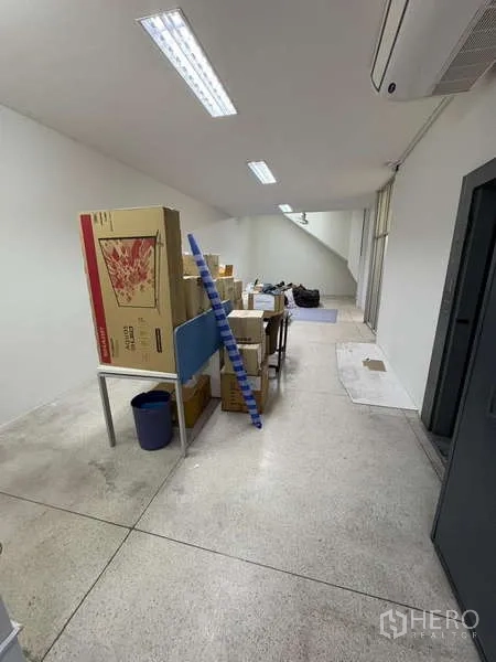 独立商业地产 出租在Khlong Toei, Bangkok - 狭长明亮的工作区，荧光灯顶，堆放纸箱。