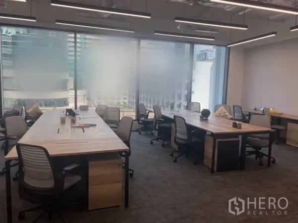 办公空间 出租在Pathum Wan, Bangkok - 开放式办公室，长木桌与人体工学椅，落地窗带来城市景观。