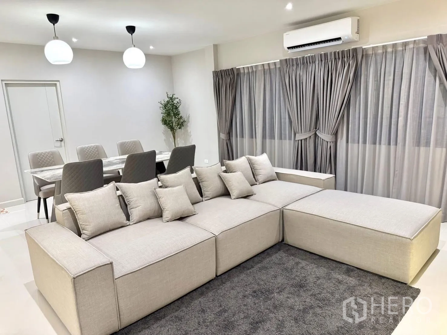 Detached House for rent in Bang Phli, Samut Prakan - Open-plan living and dining with marble-top table, pendant lights, large sectional sofa and curtains.