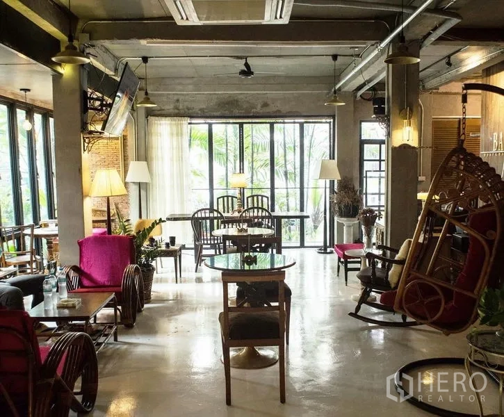 店屋 出租或出售在Din Daeng, Bangkok - 咖啡馆风格的一层，大面积落地窗、混凝土天花、藤制座椅与吊椅。