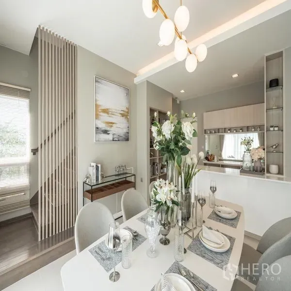 Detached House for rent in Samut Prakan - Dining area beside a pantry with built-in shelving and a slatted staircase divider.