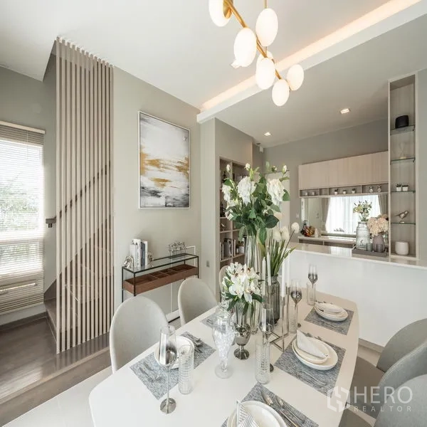 Detached House for rent in Samut Prakan - Dining area beside a pantry with built-in shelving and a slatted staircase divider.