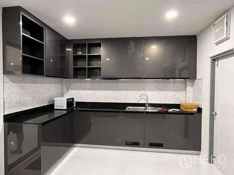 Detached House for rent - L-shaped built-in kitchen with high-gloss cabinetry, black countertops and patterned backsplash.