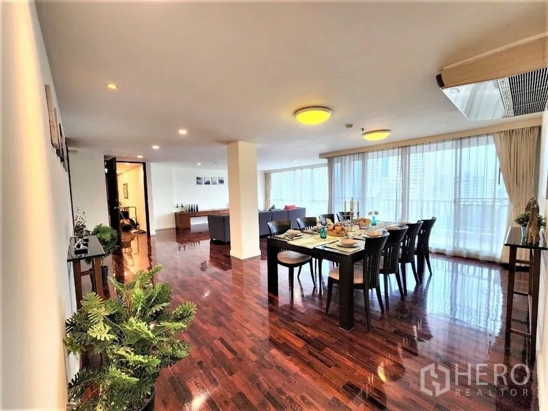 Condominium for rent in Bang Rak, Bangkok - Open-plan dining and living area with large windows, set dining table and polished wooden flooring.