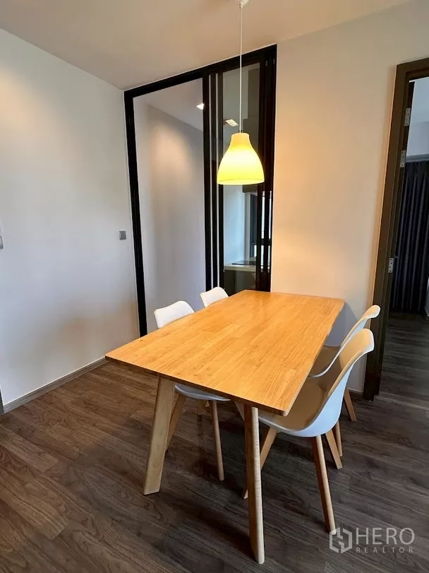 Condominium for rent in Chatuchak, Bangkok - Minimal dining set with warm pendant lighting and dark frame doors.