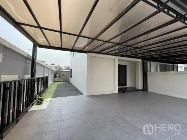 Home Office for rent in Khan Na Yao, Bangkok - Covered carport with tiled floor and a narrow side lawn at the entrance.