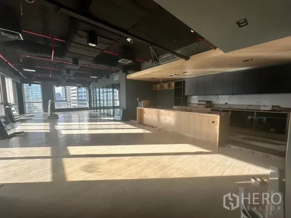 Office Space for rent in Bang Rak, Bangkok - Sunlit open-plan office featuring a bar-style pantry and Bangkok skyline in the background.