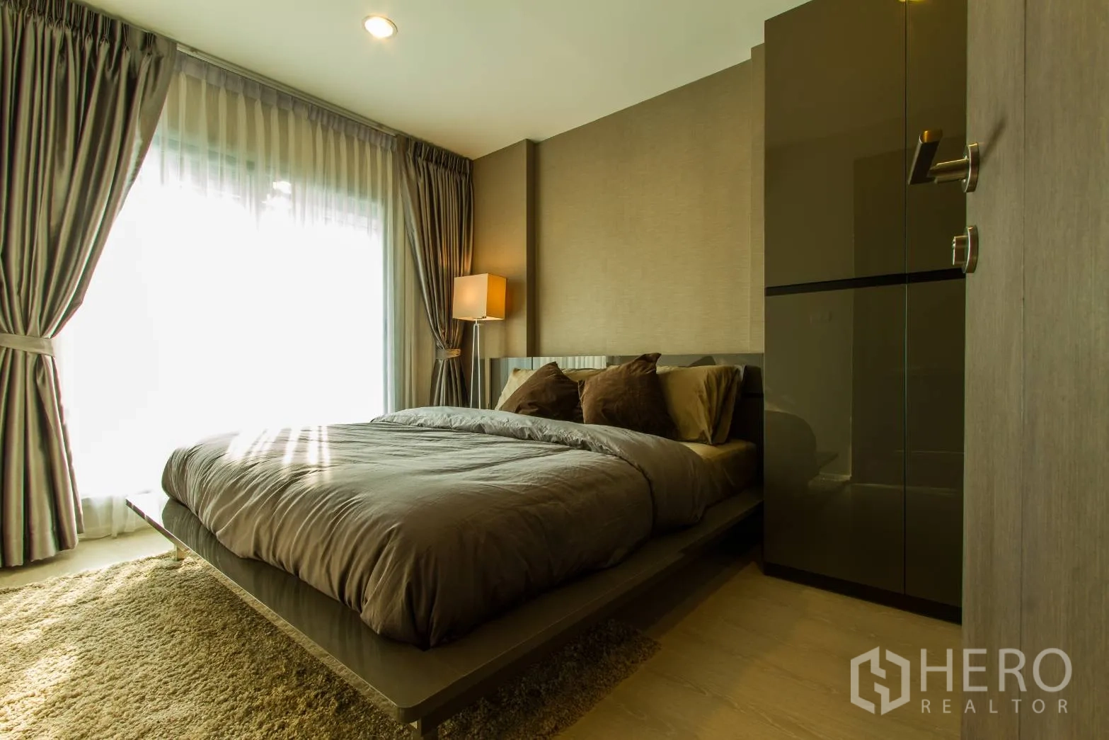 公寓 出租或出售在Sathon, Bangkok - 温暖卧室，大床、落地窗帘、柔和灯光与内置衣柜。