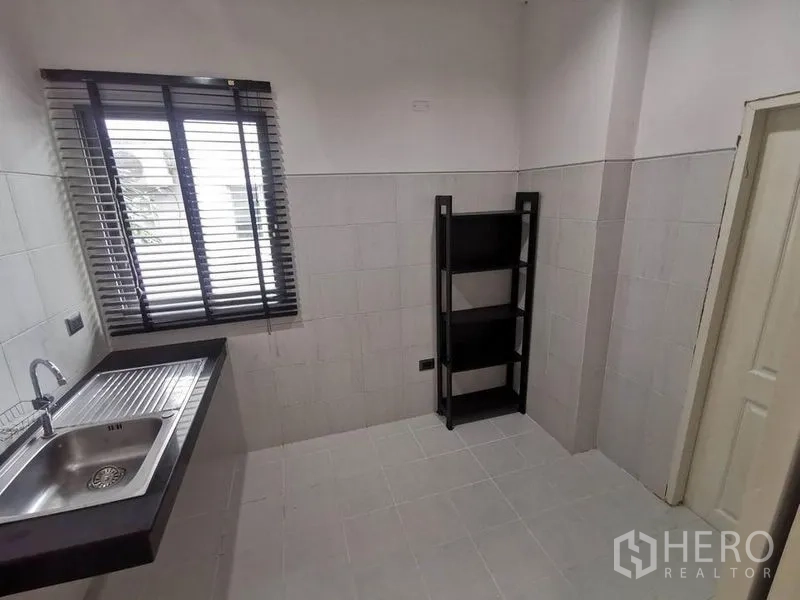 Detached House for rent in Prawet, Bangkok - Simple separate kitchen with stainless sink, tiled walls and window blinds.