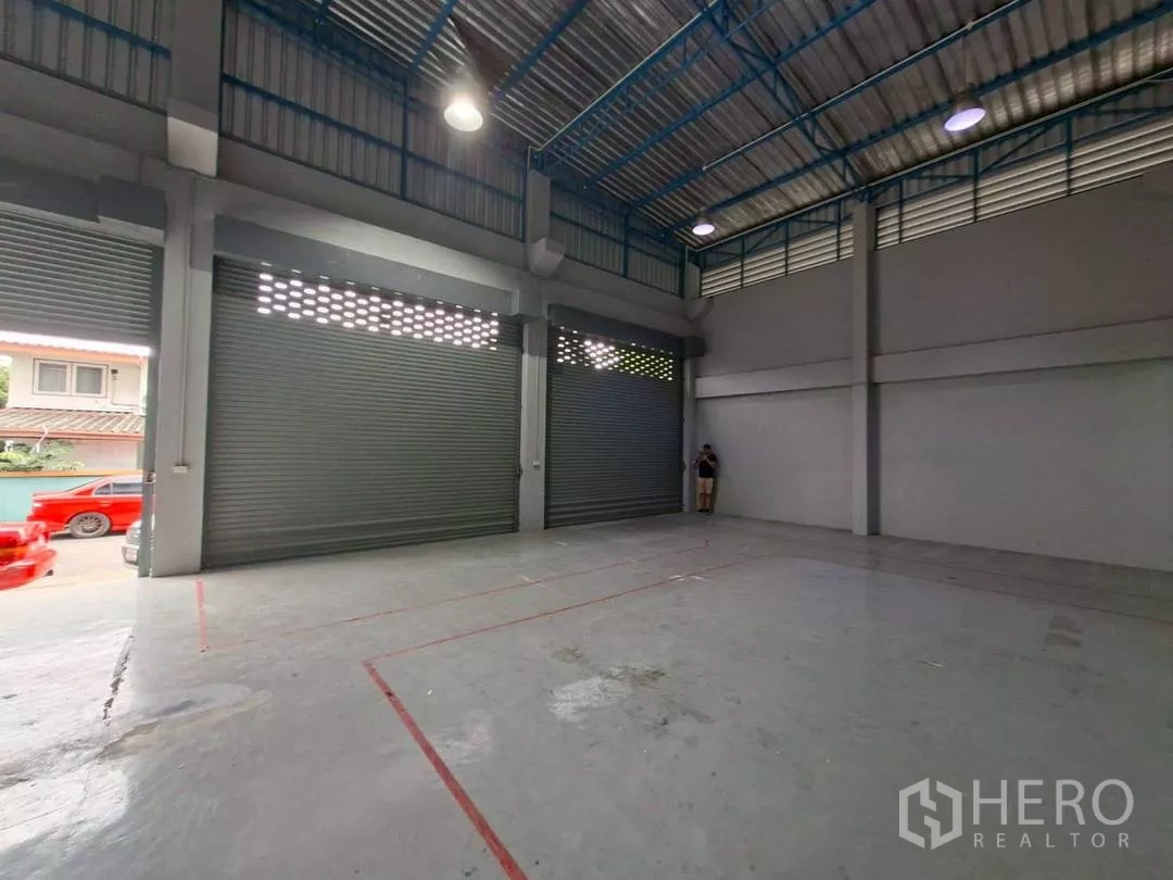 Warehouse for rent in Suan Luang, Bangkok - Spacious warehouse floor with closed shutters and tall metal roof.