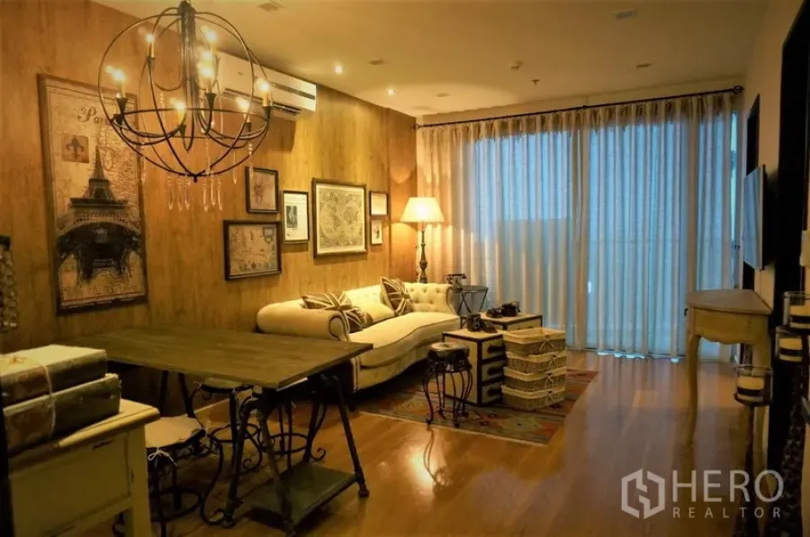 คอนโด ให้เช่าในWatthana, Bangkok - ห้องนั่งเล่นโทนอุ่น ผนังไม้ โคมไฟระย้า โซฟาครีม และผ้าม่านโปร่งแบบเต็มผนังในคอนโดกรุงเทพฯ