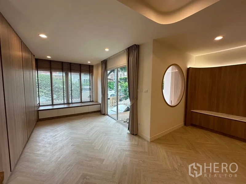 Home Office for rent in Khlong Toei, Bangkok - Ground-floor living room with sliding doors to the porch, window bench and warm wood accents.