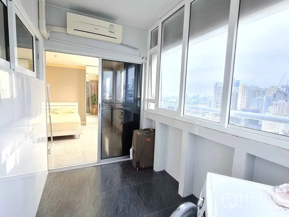 Condominium for rent in Khlong Toei, Bangkok - Enclosed sunroom with sliding doors and wide windows facing the city.