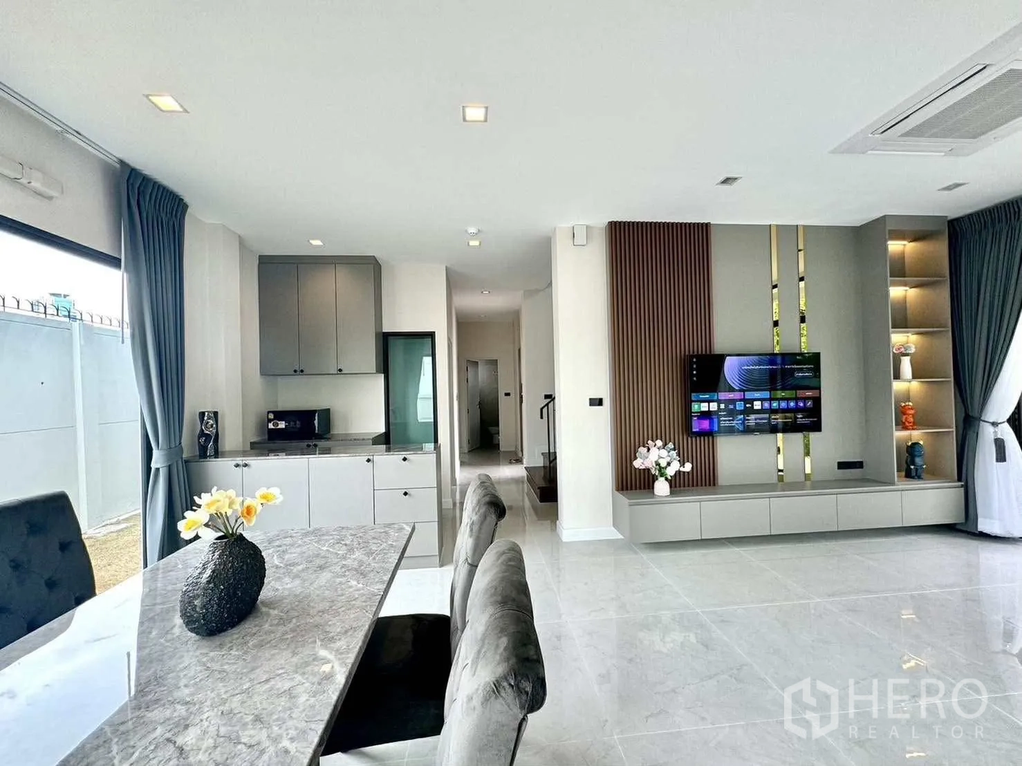 Detached House for rent in Bang Phli, Samut Prakan - Open-plan living and dining area with marble-top table, sofa and TV feature wall.