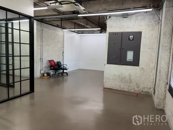 Office Space for rent in Watthana, Bangkok - Open-plan office with polished concrete floors, exposed ceiling, LED lights and a glass-partitioned room.