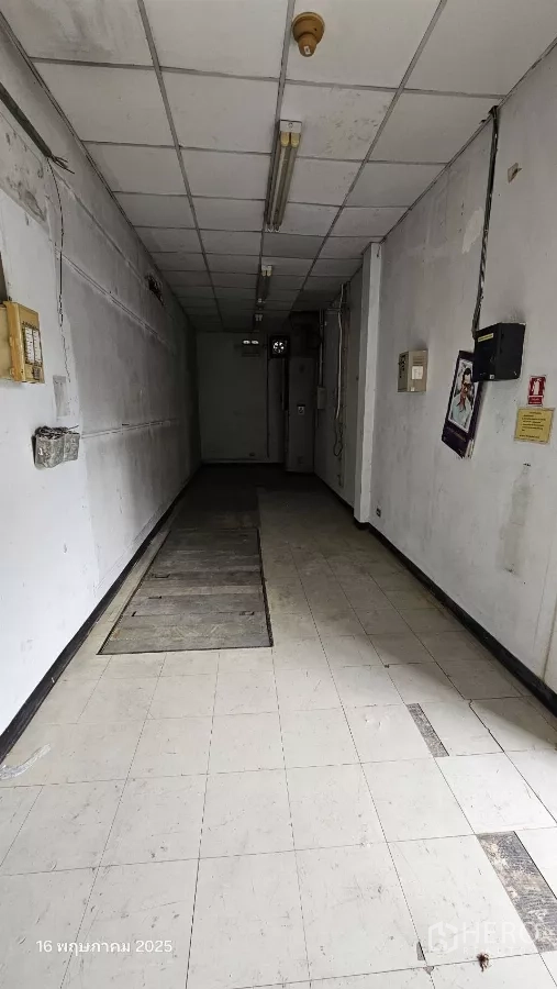 Retail Space for rent in Phra Khanong, Bangkok - Narrow corridor with tiled floor, utility panels and overhead tube lights.