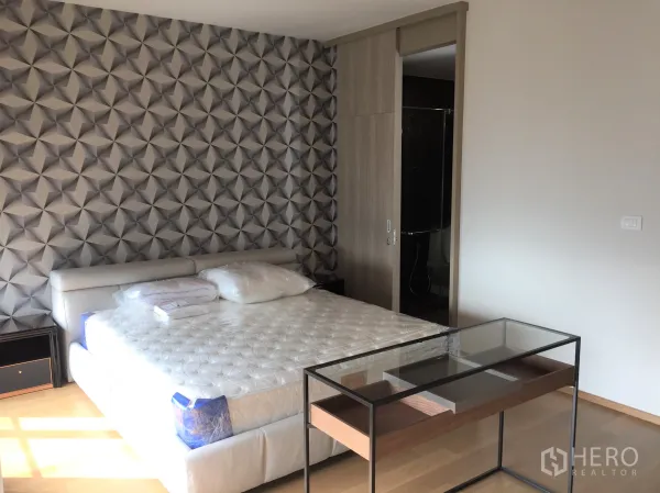 คอนโด ให้เช่าในPathum Wan, Bangkok - ห้องนอนหลัก ผนังลายเรขาคณิต เตียงคิงไซส์ และประตูบานเลื่อนเข้าสู่อาบน้ำ