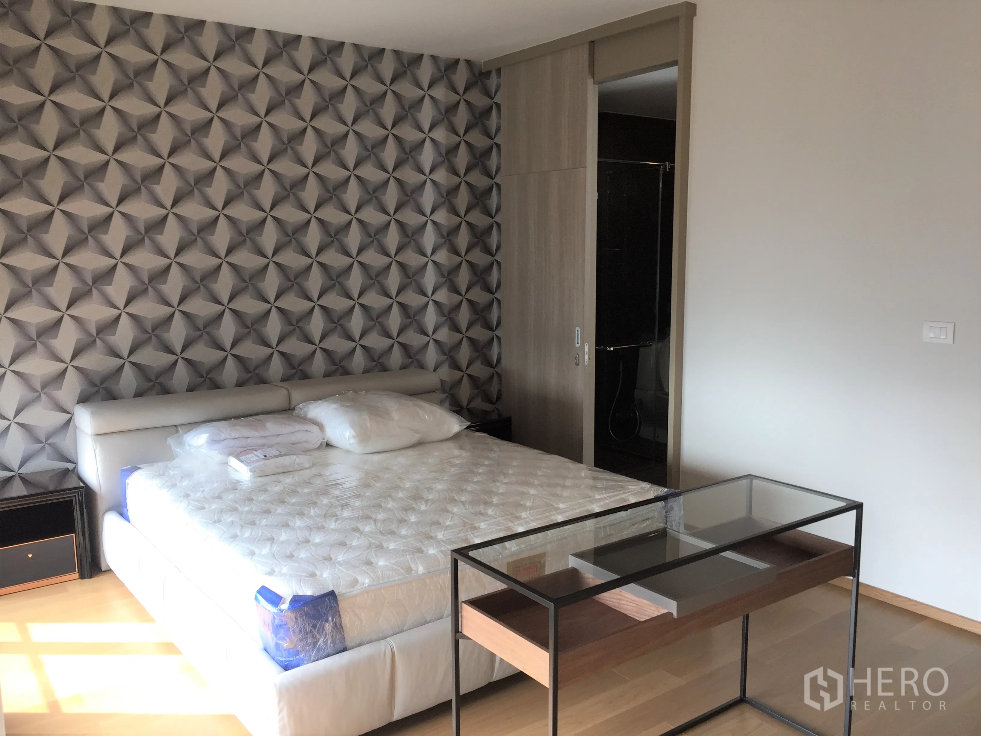 คอนโด ให้เช่าในPathum Wan, Bangkok - ห้องนอนหลัก ผนังลายเรขาคณิต เตียงคิงไซส์ และประตูบานเลื่อนเข้าสู่อาบน้ำ