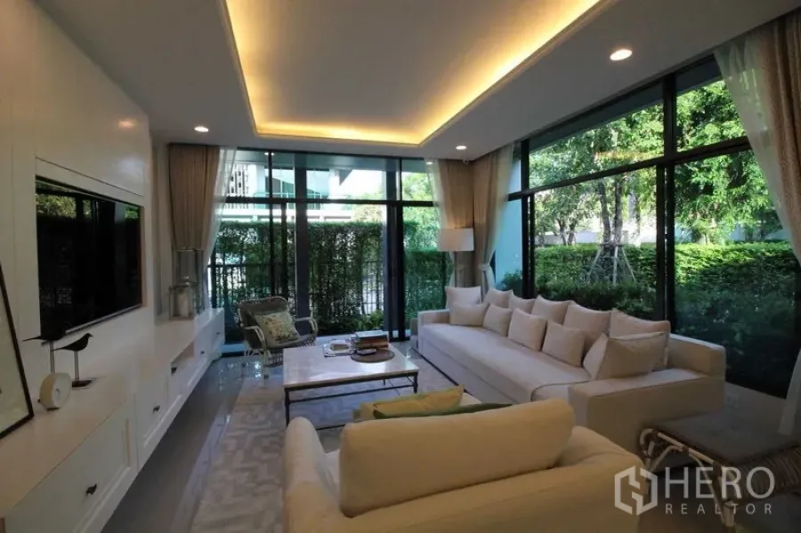 独立式住宅 出租在Prawet, Bangkok - 客厅一角，落地窗环绕，绿意景观。