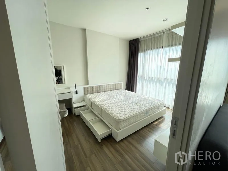 公寓 出租在Khlong Toei, Bangkok - 采光充足的主卧，带抽屉收纳床和转角大窗配纱帘。