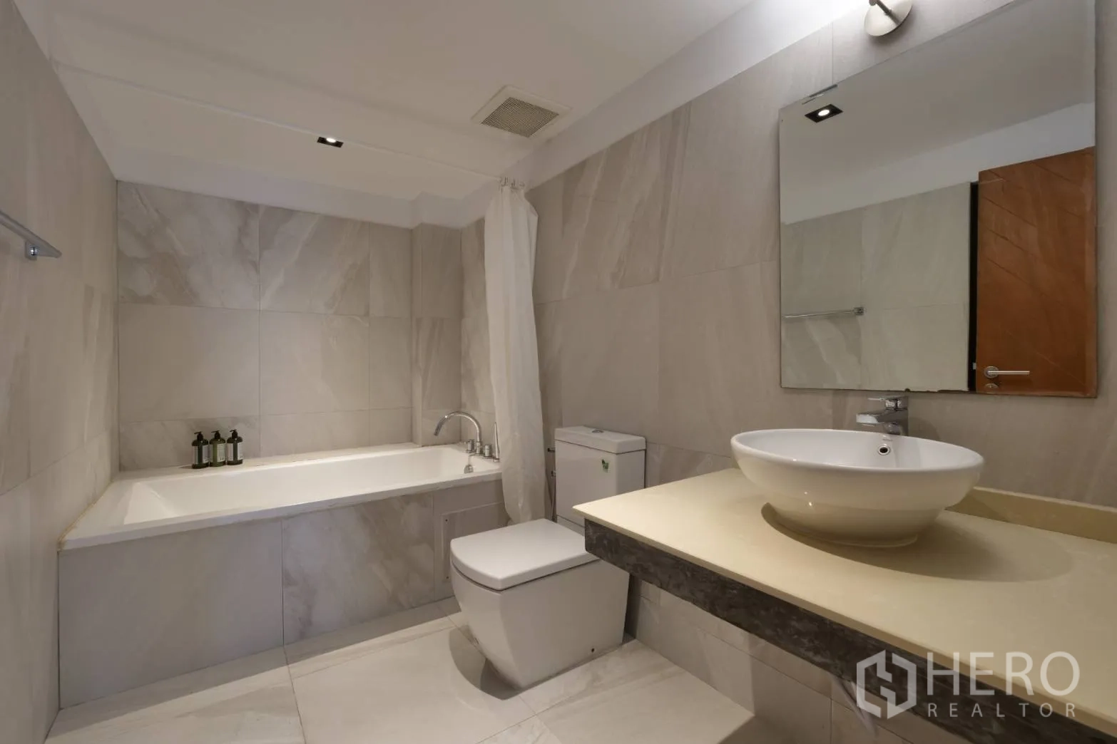 Townhouse for rent in Khlong Toei, Bangkok - Modern bathroom with bathtub, vessel sink and neutral wall tiles.