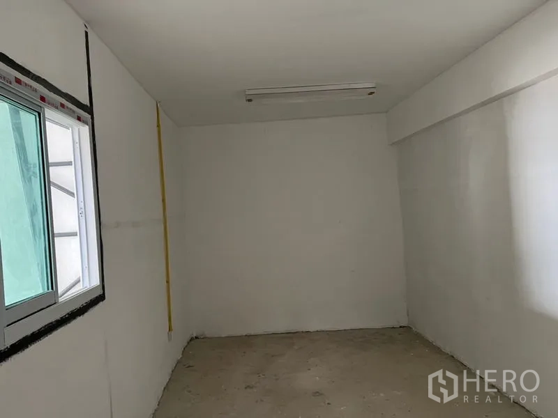 Warehouse for rent in Suan Luang, Bangkok - Compact office room inside the warehouse with sliding window, white walls, and ceiling light.