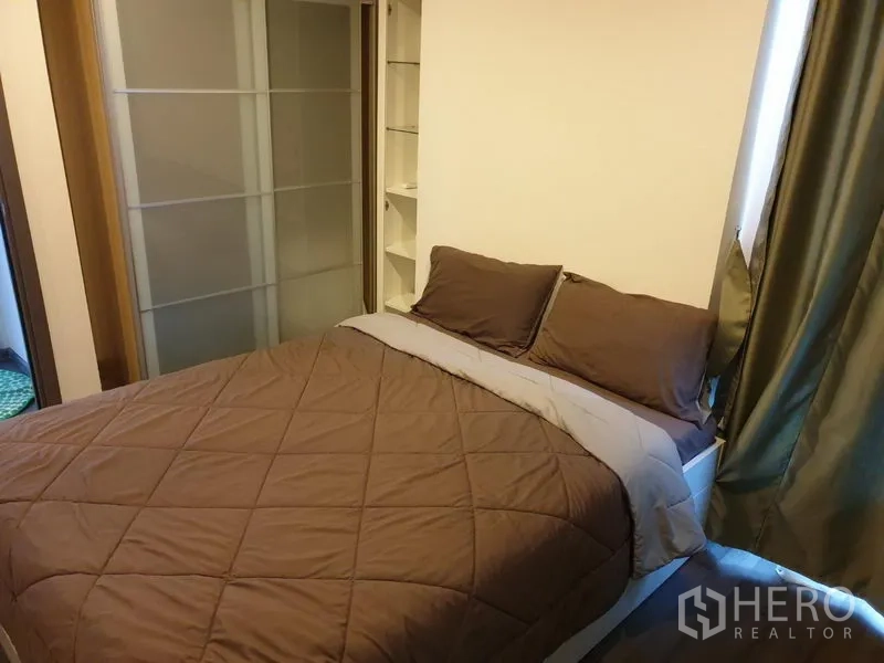 Condominium for rent in Watthana, Bangkok - Master bedroom with double bed, brown bedding, sliding wardrobe, and shelving.