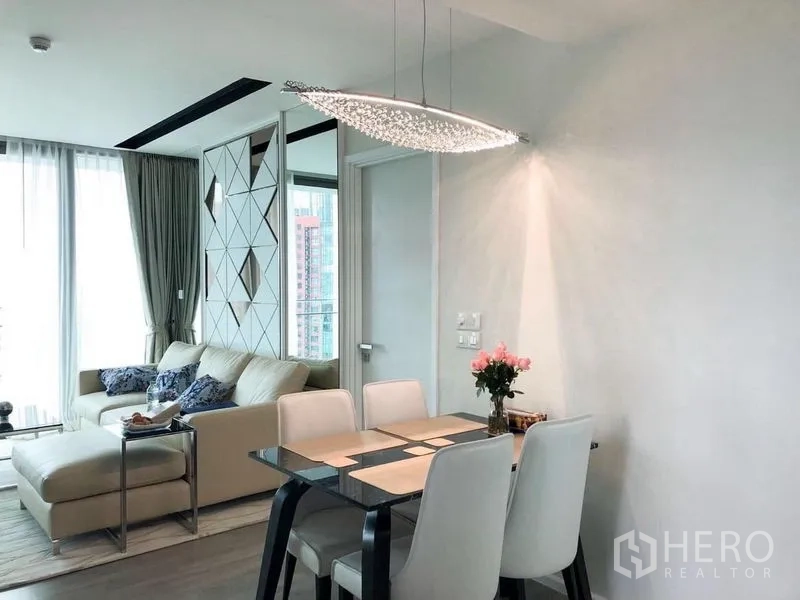 Condominium for rent or sale in Watthana, Bangkok - Bright dining corner with four-seat table under sculptural pendant and balcony windows.