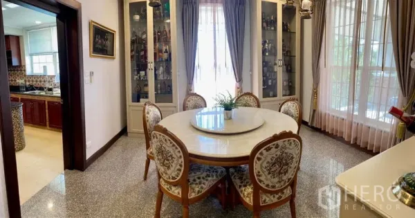 Detached House for sale in Bang Bo, Samut Prakan - Bright dining room with a round table, glass display cabinets, and entry to the kitchen.