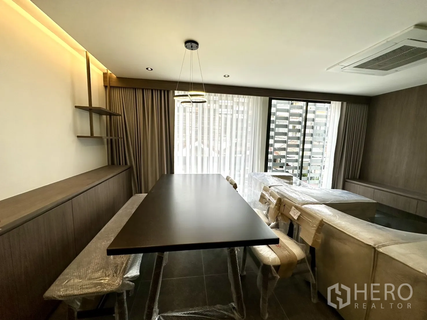 สำนักงานที่บ้าน ให้เช่าในPhra Khanong, Bangkok - มุมรับประทานอาหาร โต๊ะยาว โคมไฟแขวน และผ้าม่านโปร่งติดระเบียง