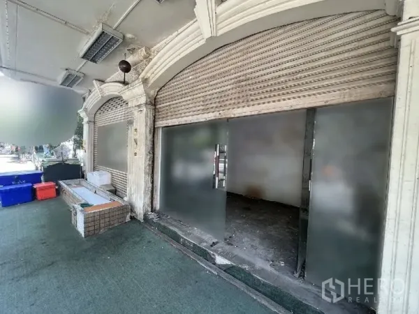 店屋 出租在Watthana, Bangkok - 临街门面，玻璃入户门与金属卷帘门，拱形装饰。