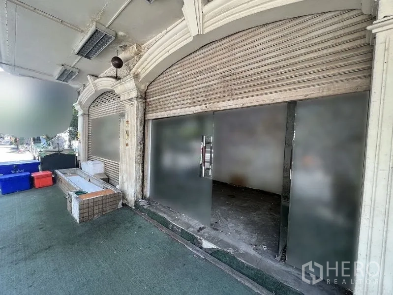 店屋 出租在Watthana, Bangkok - 临街门面，玻璃入户门与金属卷帘门，拱形装饰。