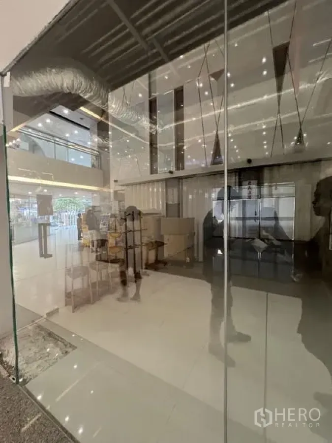 零售空间 出租 - 近距离拍摄的落地玻璃立面，可见室内灯光与中庭环境。